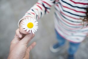 child receiving flower from parent